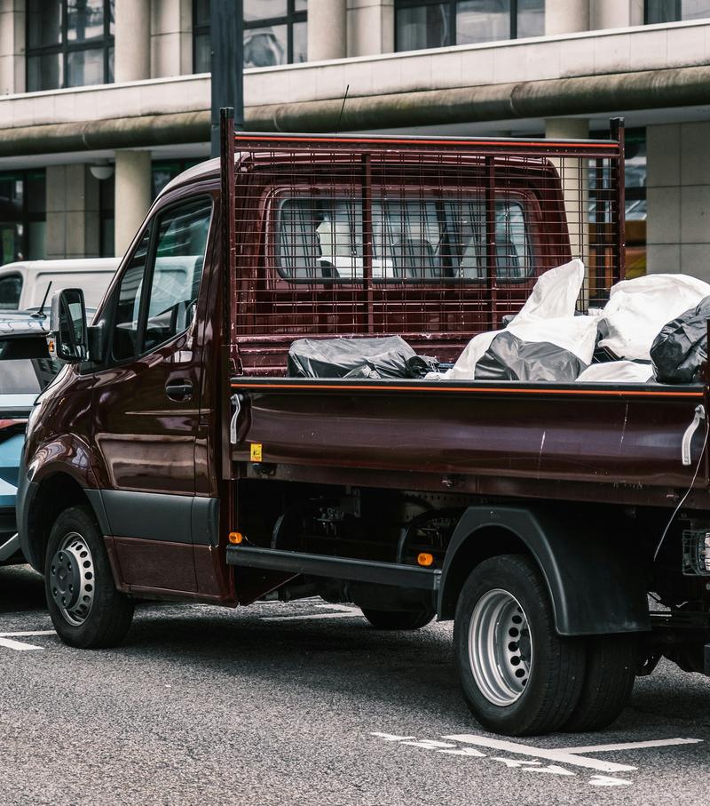 Caged dropside truck loaded with bagged waste