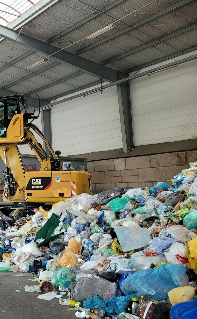 Material handler sorting mixed waste in a recycling hall