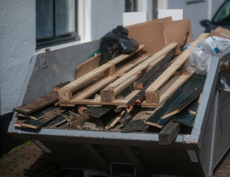 Skip loaded with timber offcuts and bagged rubbish